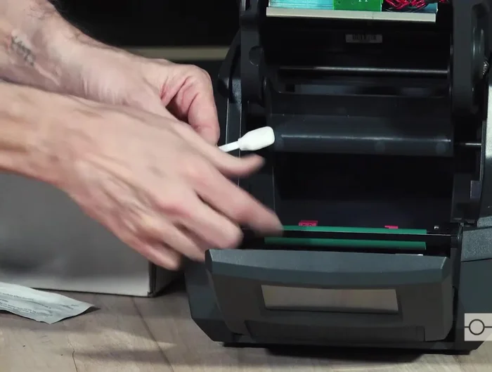 Clean the print roller using even pressure, manually advancing it with your thumb and forefinger until all surfaces are clean. Ensure the reflex sensor window is clear.