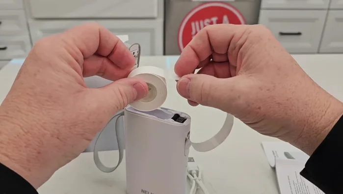 Insert the printer tape into the machine, ensuring it's tightly rolled and slightly extends from the machine.