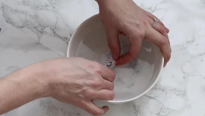 Gently peel off the paper backing from the label under lukewarm water. For inkjet printers, some ink may come off, requiring touch-up with a Sharpie after drying completely.